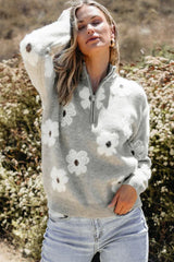 Woman wearing a gray floral print quarter-zip knit sweater with light wash denim jeans.
