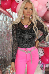 Woman wearing a black rhinestone mesh bodysuit with pink pants and jewelry