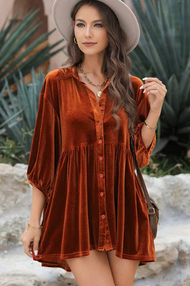 Front view of a woman in an orange velvet babydoll dress, showcasing the button-down front and tiered skirt.