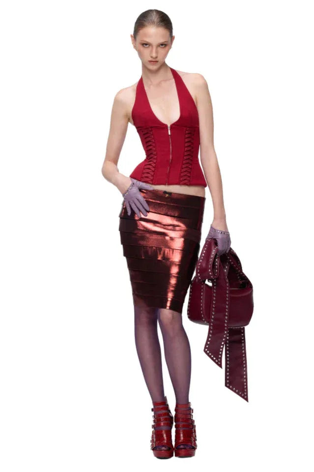 Full-body view of a model wearing a red halter corset top with a metallic red pencil skirt, purple tights, and purple gloves.