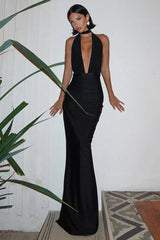 Woman in a long black satin halter dress with a deep V-neckline and a flowing skirt.