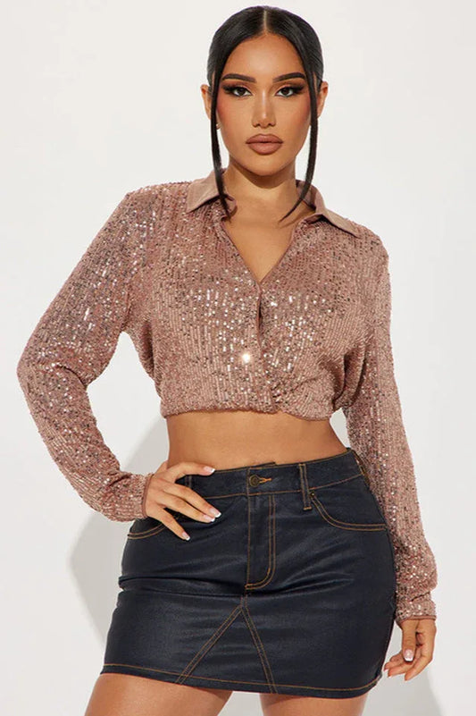 Woman wearing a rose gold sequined cropped shirt and dark denim mini skirt, front view.
