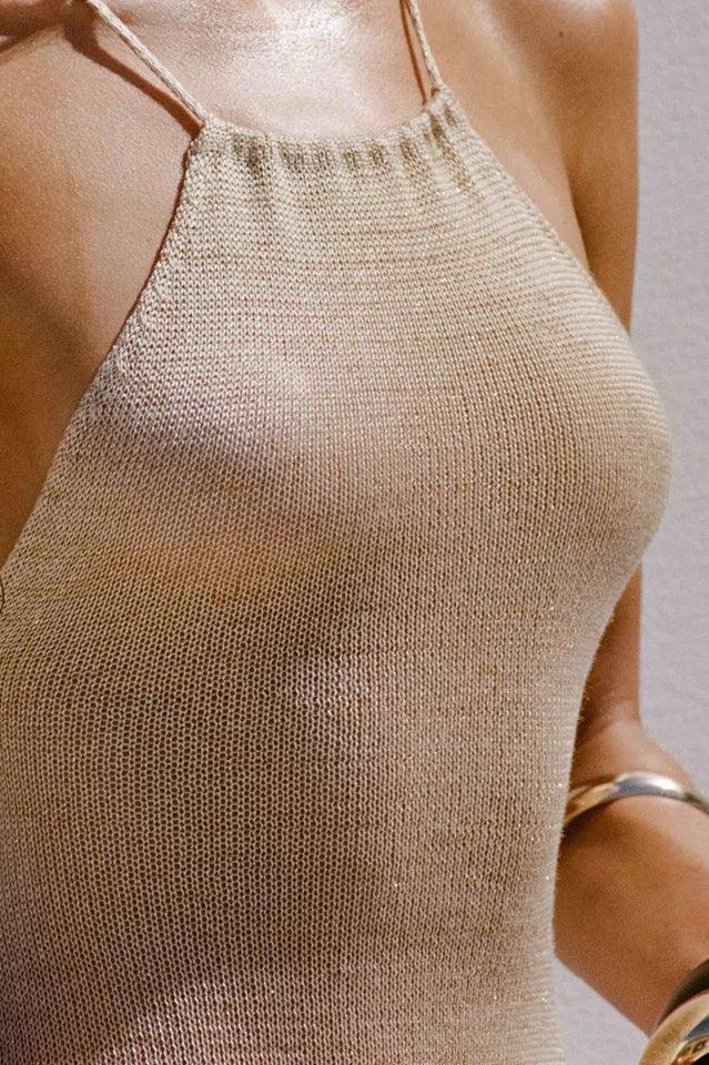 Detail of the halter neckline of a sheer, metallic knit maxi dress.