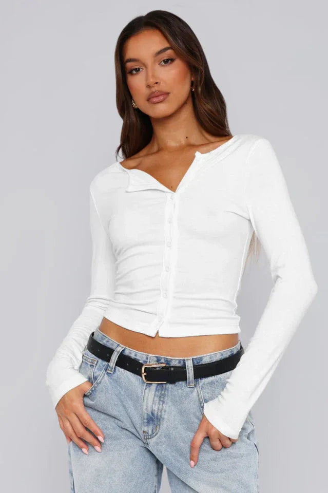 Woman wearing a white long-sleeve cropped top with button-up front and blue jeans