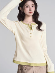 Woman wearing a cream long-sleeved shirt with green trim and buttons, paired with khaki pants.