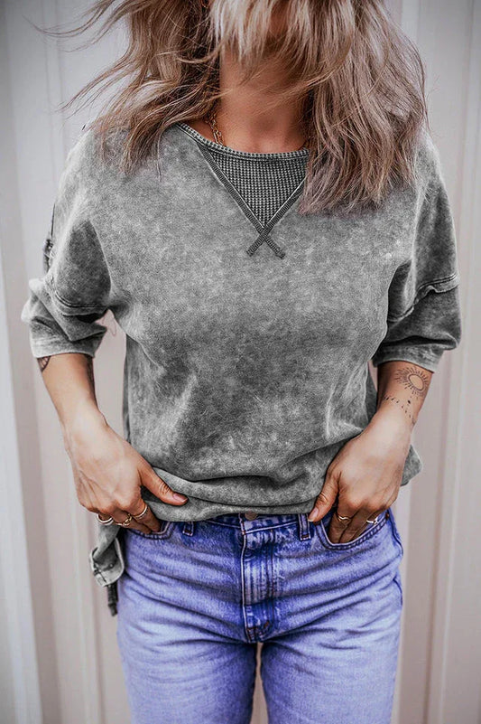 Woman wearing a grey acid wash oversized t-shirt with blue jeans, hands in pockets