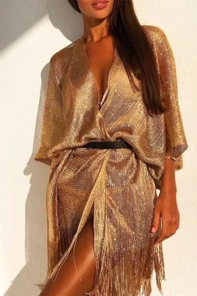 Woman wearing a gold fringed kimono dress cinched with a black belt.