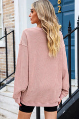 Back view of a woman wearing a pink ribbed long-sleeve oversized tunic and black shorts