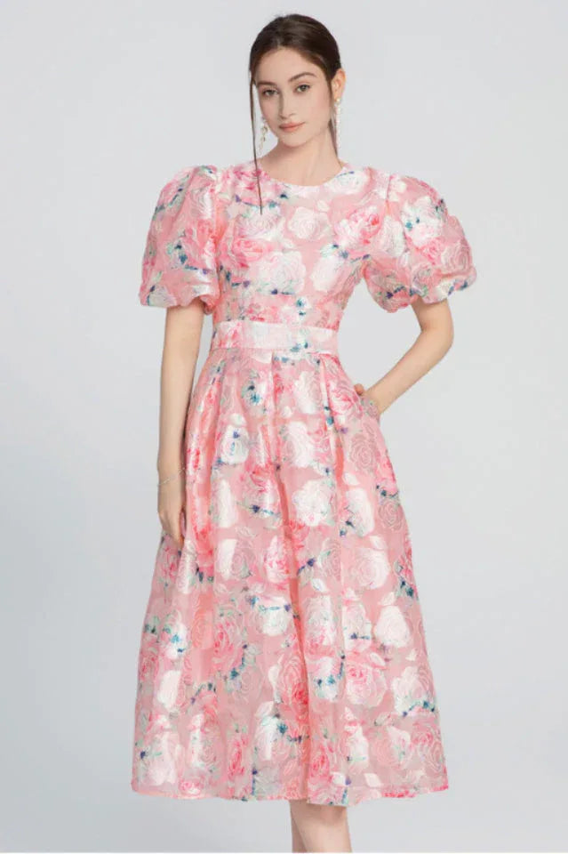 Full length view of a woman in a pink floral midi dress with puff sleeves.
