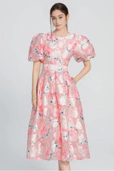 Full length view of a woman in a pink floral midi dress with puff sleeves.