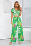 Woman wearing a green floral print two-piece set with a cropped V-neck top and wide-leg pants, front view.