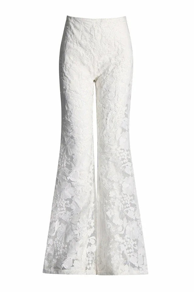 Close-up of white lace flare leg pants with floral embroidery.