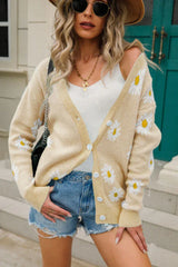 Woman wearing a beige daisy print knit cardigan with denim shorts and a necklace
