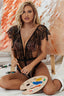 Woman in a black lace bodysuit holding a paintbrush and palette