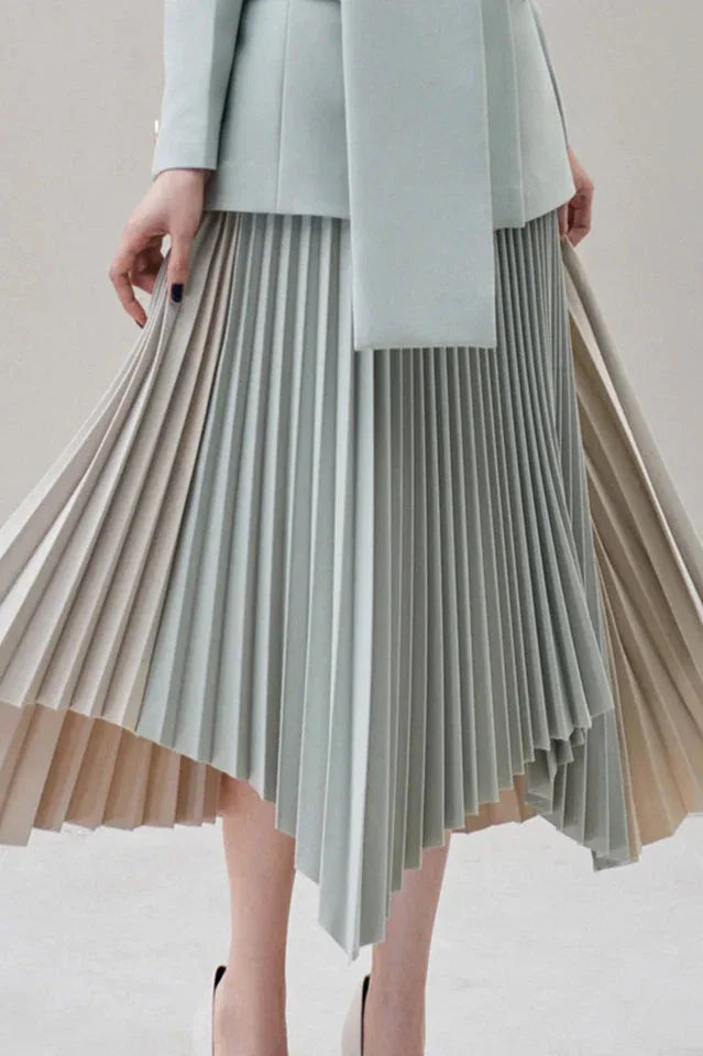 Close-up of the asymmetrical pleated skirt in light blue and beige, showing the pleats and asymmetrical hem.