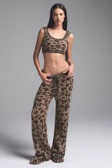 Woman wearing a leopard print fuzzy crop top and pants with slippers.
