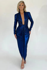 Woman wearing a long-sleeved, metallic blue, floor-length dress with a deep V-neckline and a high slit.