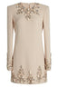 Close-up of a pale pink, long-sleeved shift dress featuring intricate crystal and pearl embellishments around the neckline and down the front.