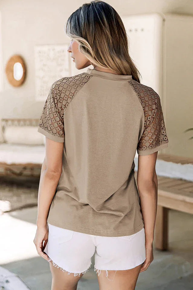 Back view of a woman wearing a taupe t-shirt with lace sleeves and white shorts.