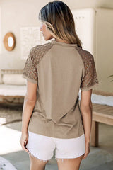 Back view of a woman wearing a taupe t-shirt with lace sleeves and white shorts.