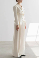 Woman wearing a white tailored suit with a peplum jacket and wide-leg trousers, side view.
