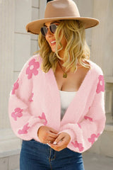 Close-up of a woman wearing a pink fluffy knit cropped cardigan with a floral print.