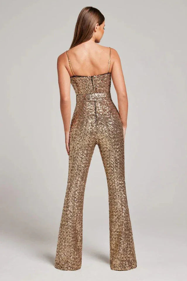 Back view of a woman wearing a gold sequined jumpsuit, showing the zipper and wide-leg silhouette.