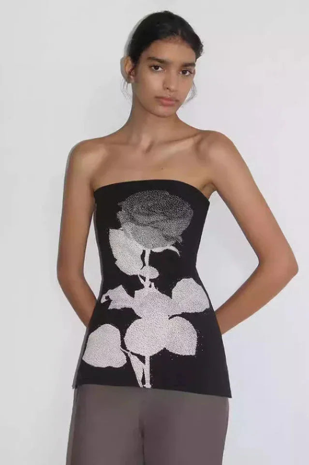 Woman wearing a black strapless tube top with a white rose graphic print.