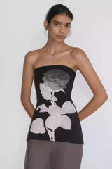 Woman wearing a black strapless tube top with a white rose graphic print.