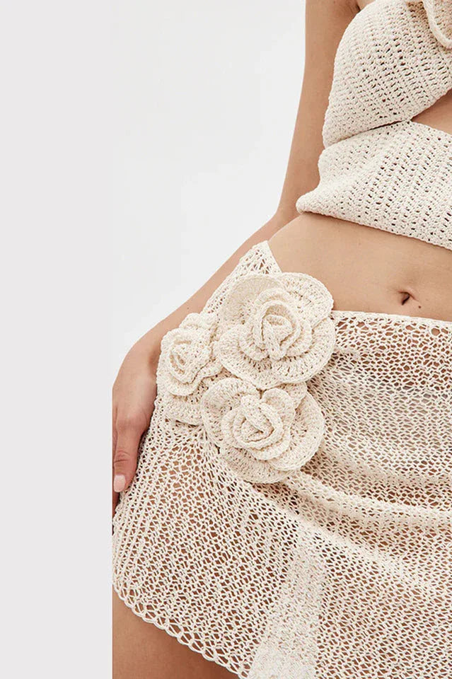 Close-up of floral appliqué on a cream crocheted mini skirt.