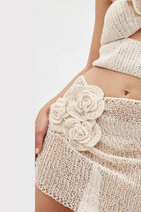 Close-up of floral appliqué on a cream crocheted mini skirt.