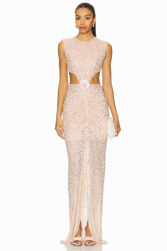 model wearing a long, sleeveless, blush pink sequined gown with cut-out details at the waist and a high slit