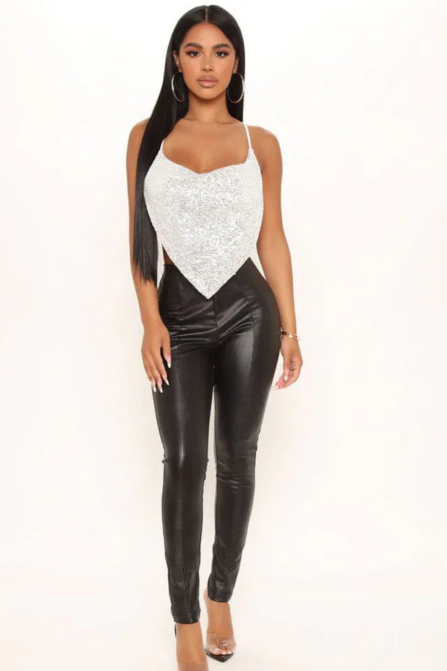 Full body shot of a woman in a silver sequined bandana top and black leather pants.