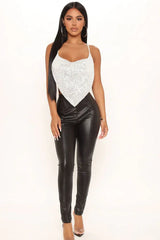 Full body shot of a woman in a silver sequined bandana top and black leather pants.