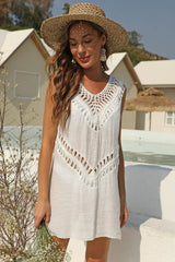 Woman wearing a white crochet trim tunic dress and straw hat, holding flowers.