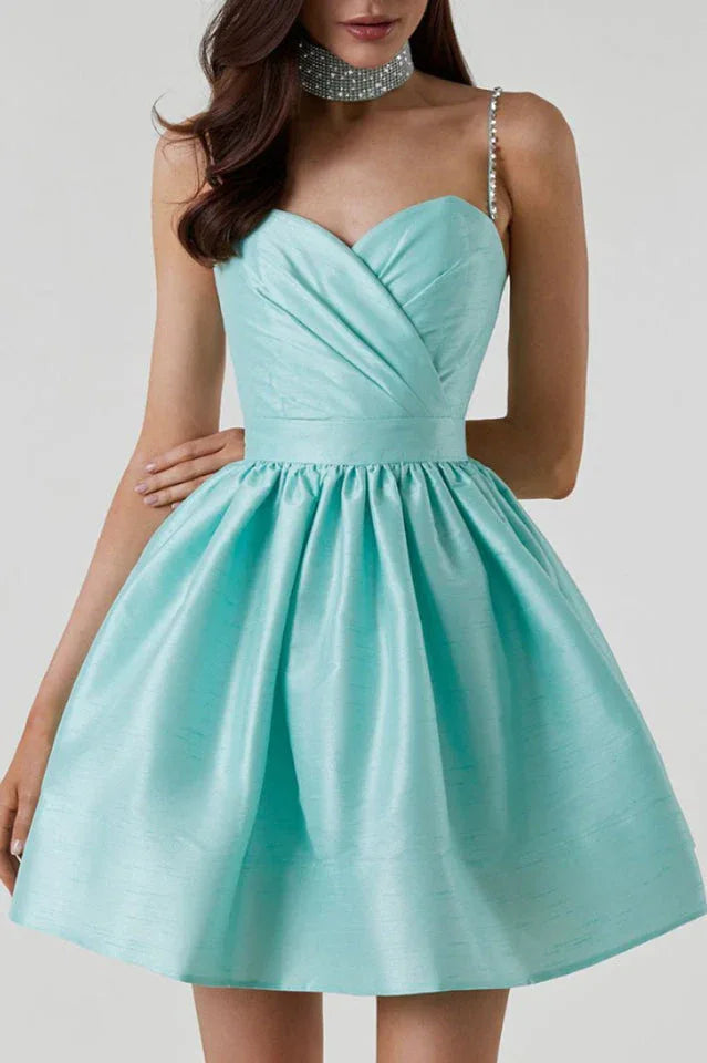 Close-up of the bodice and skirt of a short, aqua satin dress with a sweetheart neckline, ruched detailing, and embellished straps.