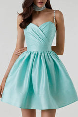 Close-up of the bodice and skirt of a short, aqua satin dress with a sweetheart neckline, ruched detailing, and embellished straps.