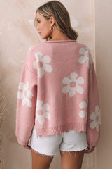 Back view of a woman wearing a pink knit sweater with a flower pattern and pearl embellishments.
