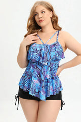 Woman wearing a blue and purple snake print ruffled tankini top with black swim shorts, front view.