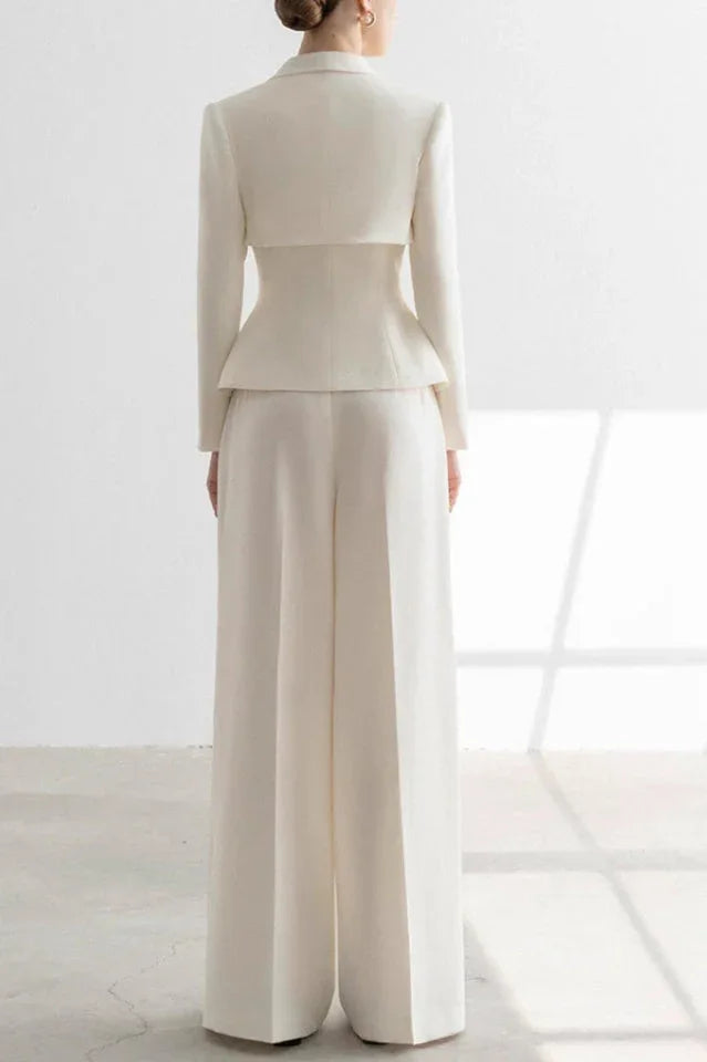 Woman wearing a white tailored suit with a peplum jacket and wide-leg trousers, back view.