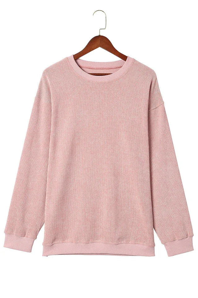 Pink ribbed long-sleeve oversized tunic hanging on a wooden hanger