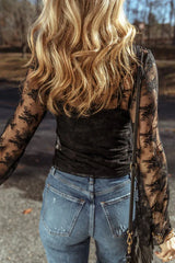 Back view of a woman wearing a black lace long-sleeved top with a scoop neckline and bell sleeves, paired with blue denim jeans.
