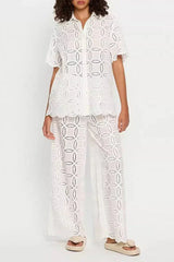 Woman wearing a white embroidered short-sleeve button-down shirt and wide-leg pants