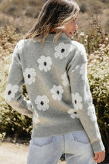 Rear view of a woman wearing a gray floral print quarter-zip knit sweater and light wash denim jeans.
