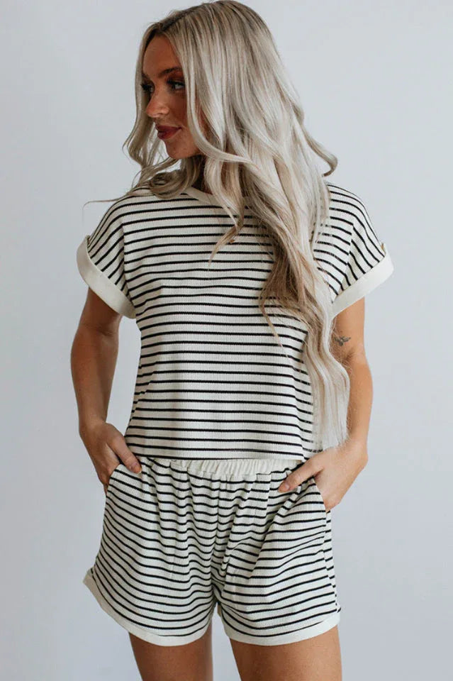 Woman wearing a black and white striped loungewear set, side view with hands in pockets