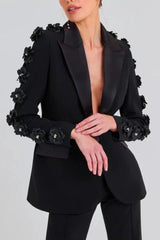 Detail shot of the hands of a woman wearing a black formal suit, showing sleeve embellishments
