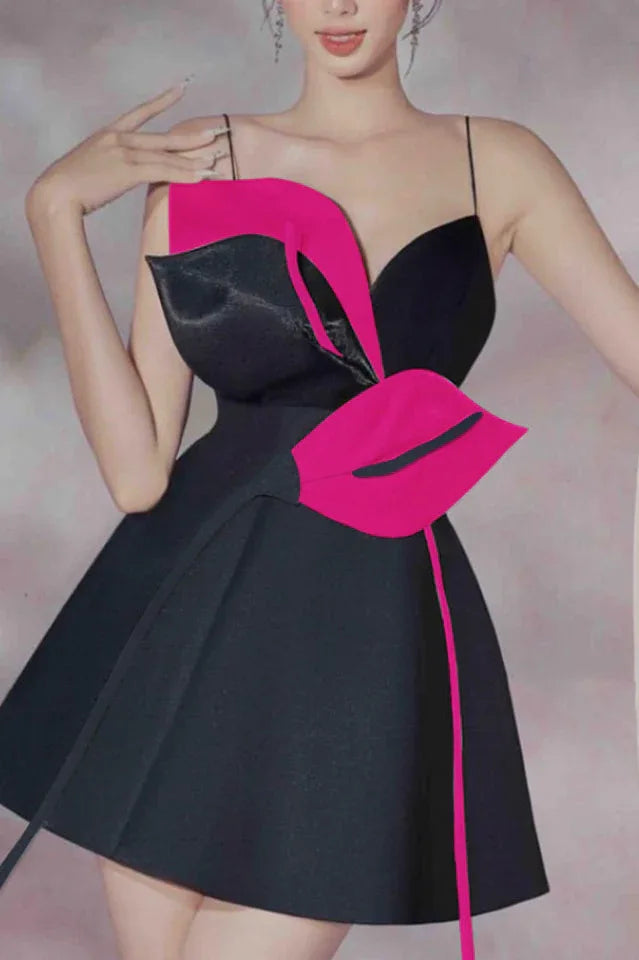 Close-up of a black mini dress with a dramatic pink and black floral applique on the bodice