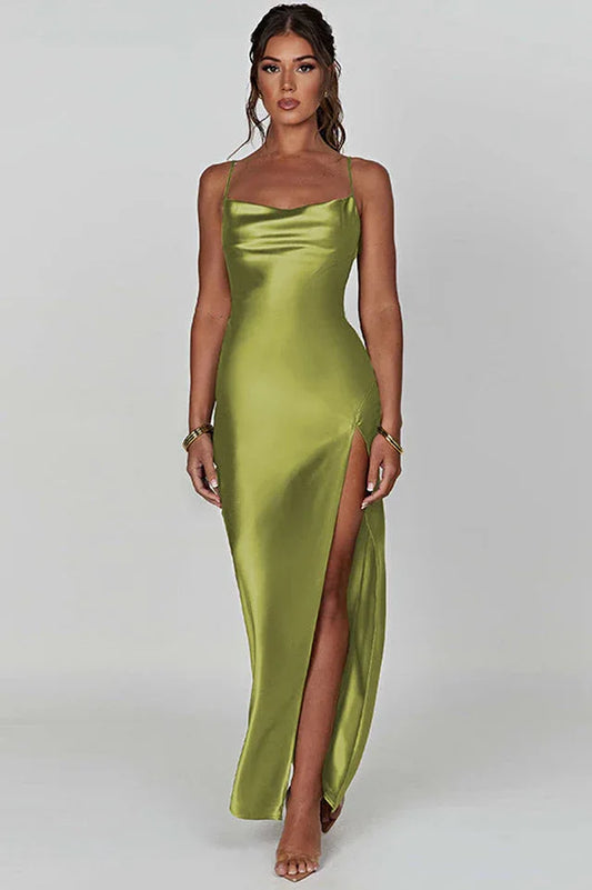 Woman wearing a long olive green satin slip dress with spaghetti straps and a high slit.