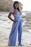 Woman wearing a blue crop top and wide leg pants on a beach