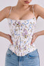 Woman wearing a floral print corset top with blue ribbon accents and a sweetheart neckline, paired with blue denim jeans.